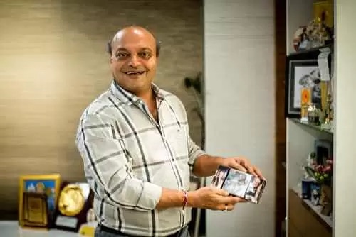 પોતાની ઓફિસમાં એક તસવીર હાથમાં લઈને સ્મિત કરતા મહેશ સવાણી