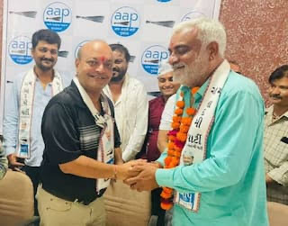 હાર પહેરેલા પાર્ટીના એક સાથી સાથે હાથ મિલાવતા મહેશ સવાણી